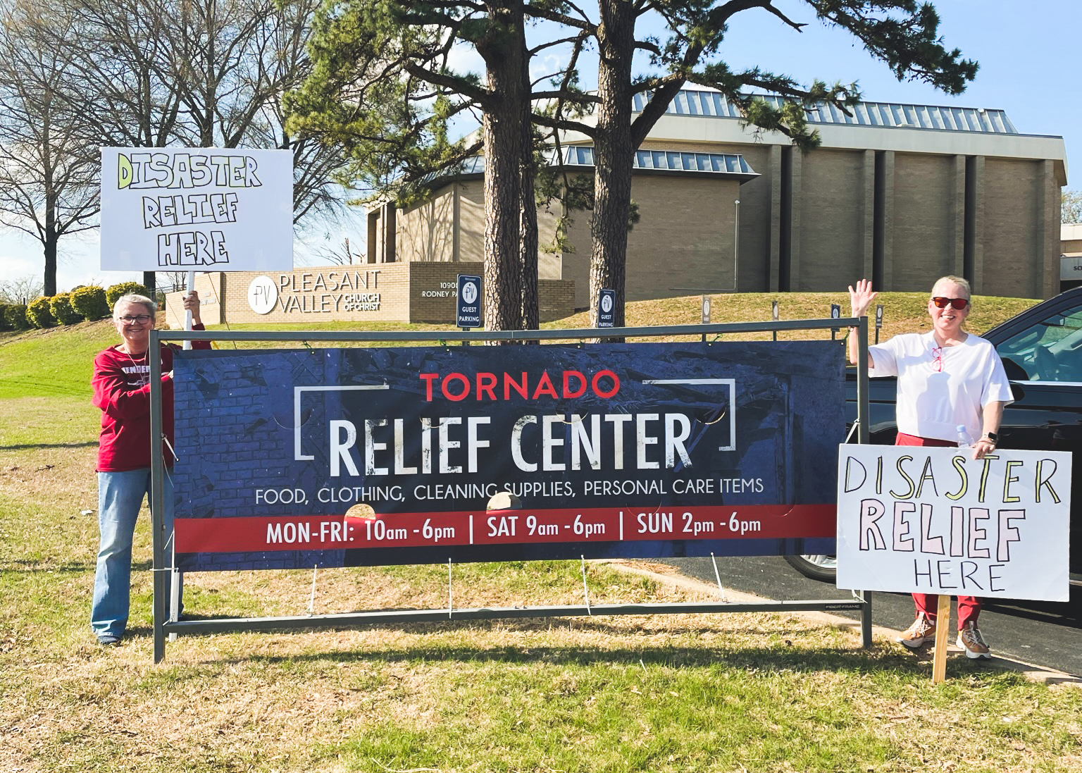 Couple next to sign at Pleasant Valley Church of Christ in Little Rock, Arkansas, that reads "Tornado Relief Center"