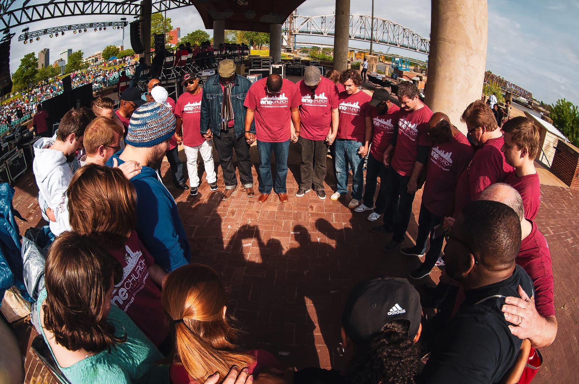 group of people in circle praying at the Little Rock Riverfront