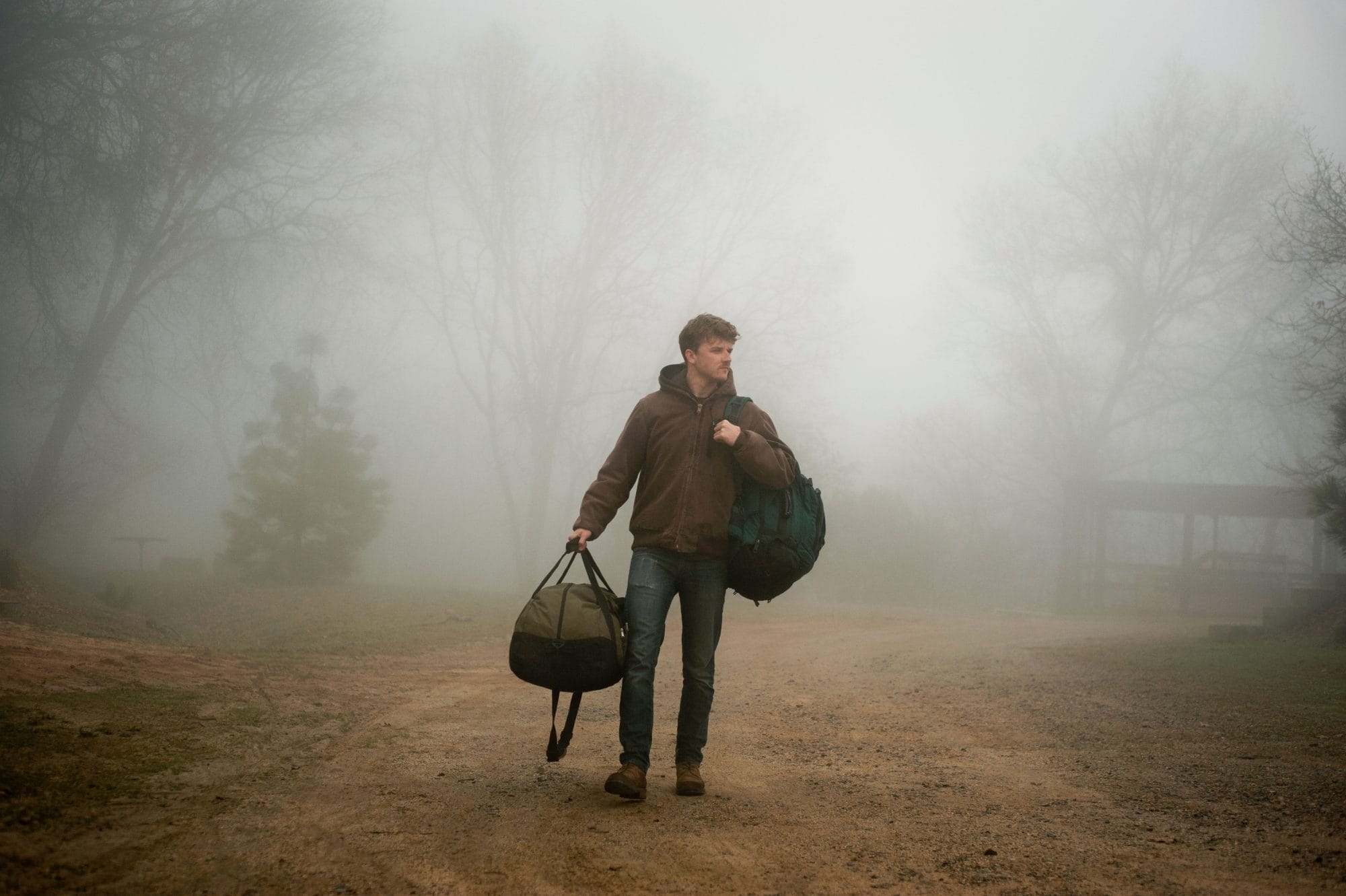 Man walkin in fog holding bags