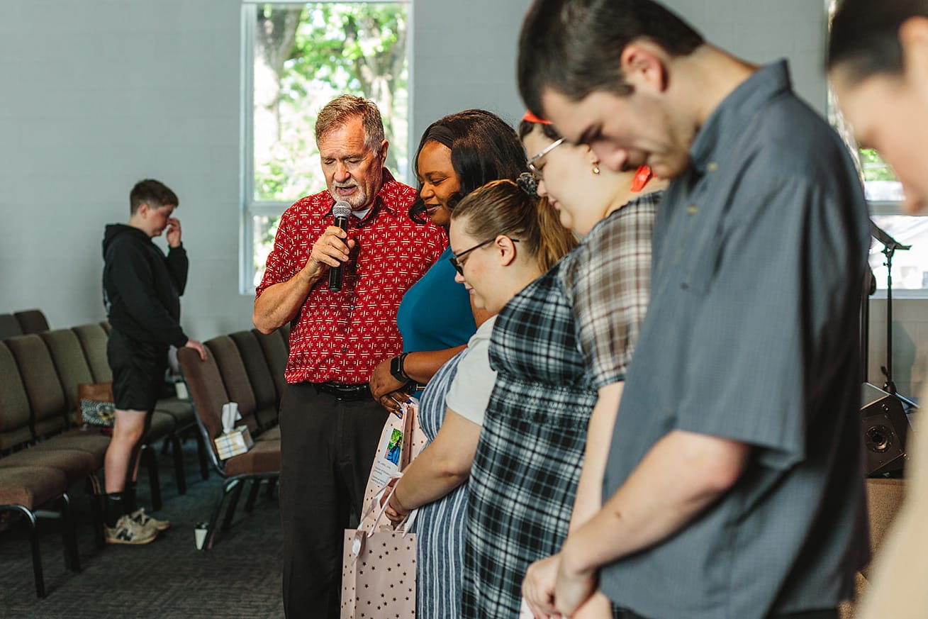Mitch Tapson praying with church members