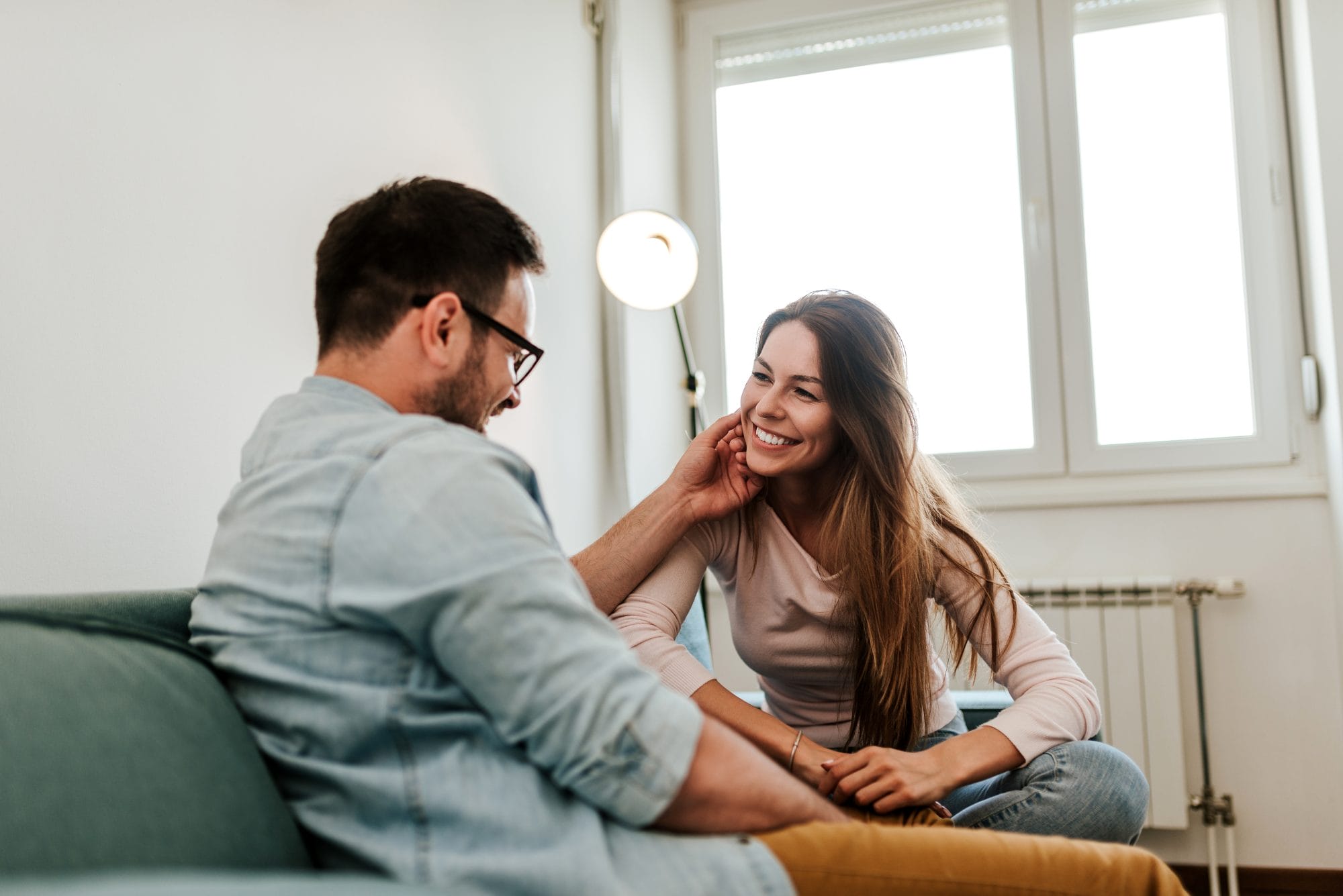 couple laughing and talking on a couch
