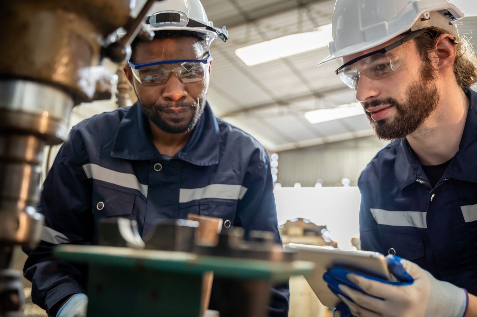 two blue collar workers looking at document