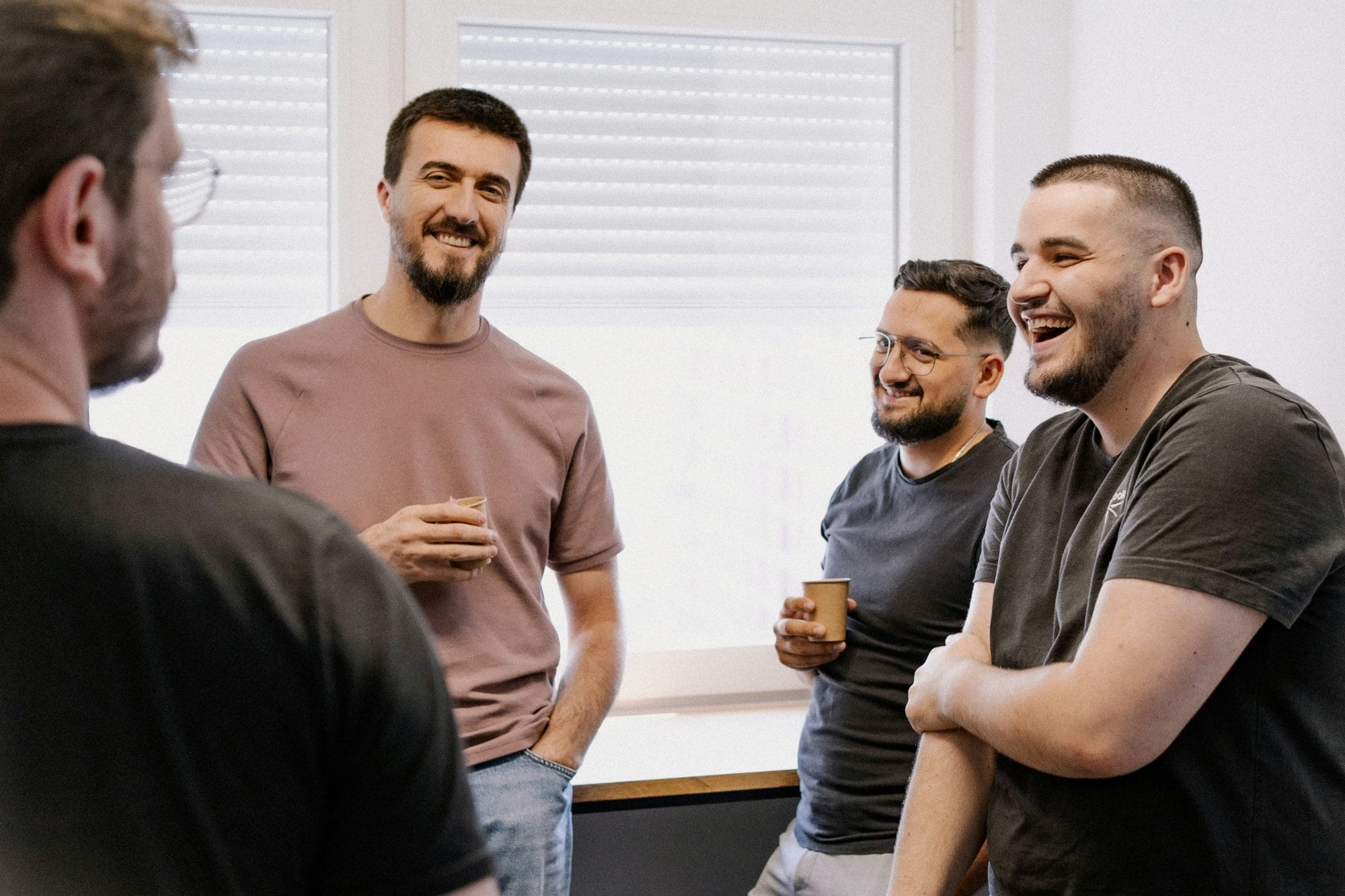 Men in a circle laughing and drinking coffee